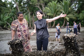 Annalena Baerbock (Bündnis 90/Die Grünen), deutsche Außenministerin, steht mit Bewohnerin Lavenia McGoon an den Grabsteinen der Siedlung Toguru, die wegen Küstenerosion überflutet wurden.