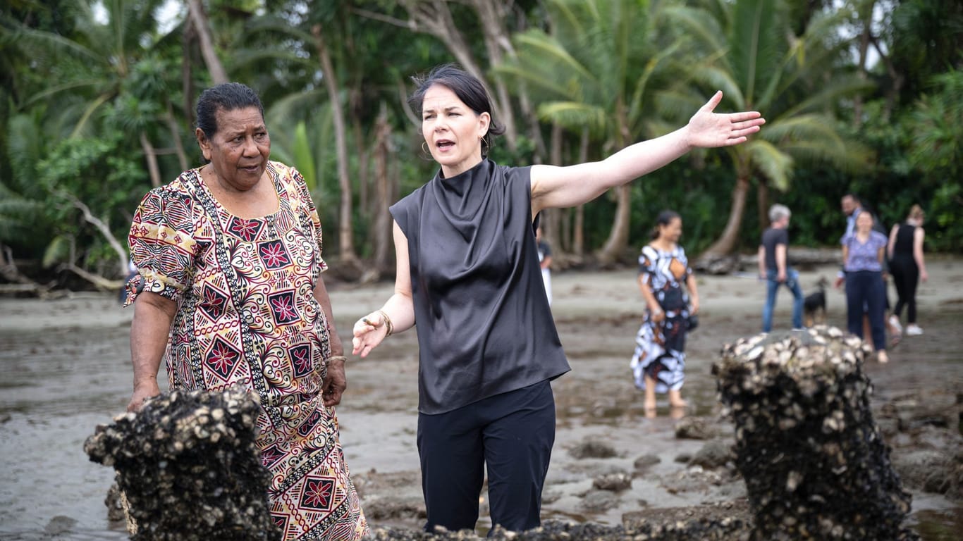 Annalena Baerbock (Bündnis 90/Die Grünen), deutsche Außenministerin, steht mit Bewohnerin Lavenia McGoon an den Grabsteinen der Siedlung Toguru, die wegen Küstenerosion überflutet wurden.