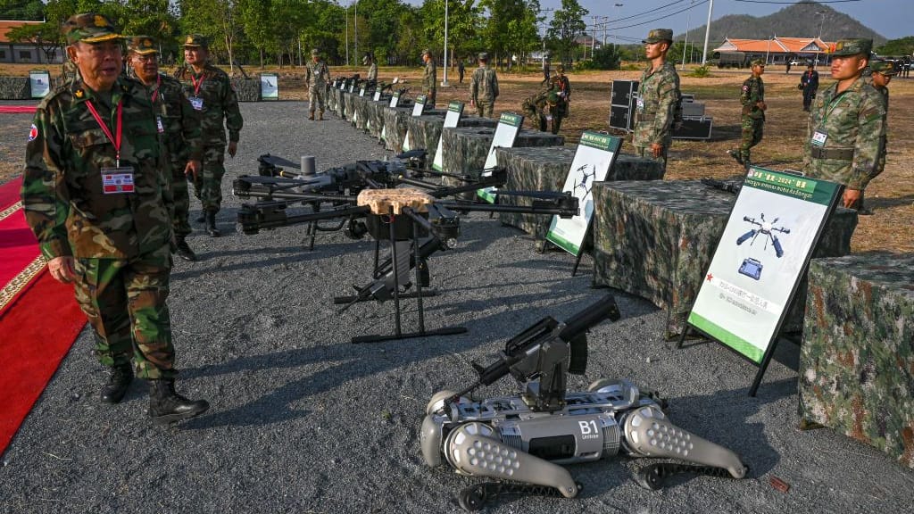 Kampong Chhnang: General Mao Sophan (l.) inspiziert einen mit Maschinengewehren ausgerüsteten Roboter-Kampfhund.