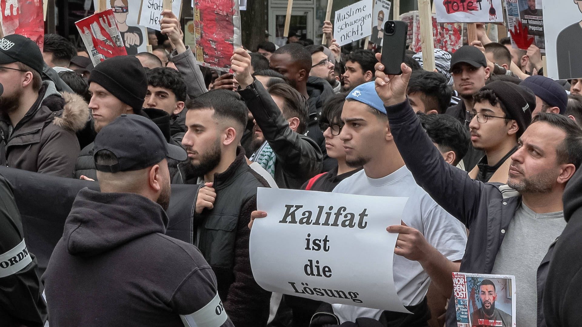 Hamburg: Teilnehmer einer Islamisten-Demo halten ein Plakat mit der Aufschrift "Kalifat ist die Lösung" in die Höhe. Hamburg: Teilnehmer einer Islamisten-Demo halten ein Plakat mit der Aufschrift "Kalifat ist die Lösung" in die Höhe.