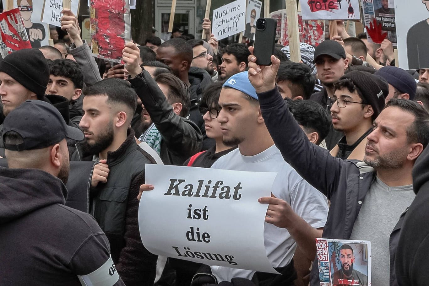 Hamburg: Teilnehmer einer Islamisten-Demo halten ein Plakat mit der Aufschrift "Kalifat ist die Lösung" in die Höhe.