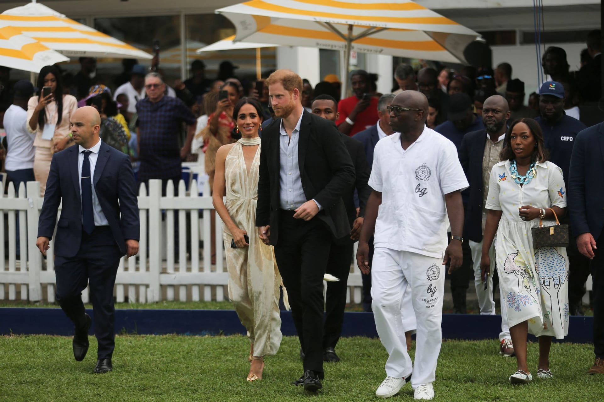 Herzogin Meghan und Prinz Harry laufen über eine Wiese bei einem Fundraiser-Polospiel in Lagos.