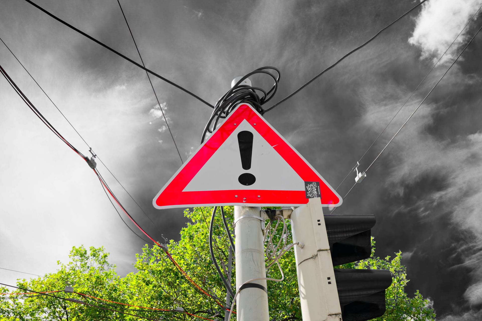 Warn-Zeichen vor einer dunklen Wolke (Symbolfoto): Am Donnerstag wird es in Teilen Bayerns ungemütlich.