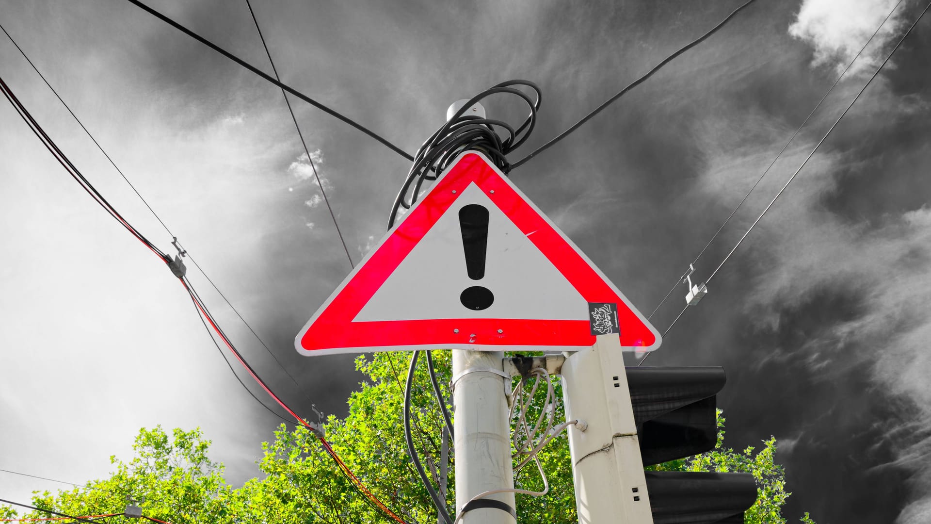 Warn-Zeichen vor einer dunklen Wolke (Symbolfoto): Am Donnerstag wird es in Teilen Bayerns ungemütlich.