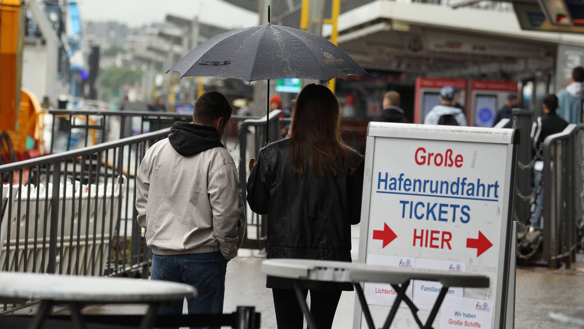 Ein Mann und eine Frau gehen mit einem Regenschirm an den Landungsbrücken entlang (Symbolbild): Eine Starkregenkarte zeigt, wo es in Hamburg gefährlich ist. Ein Mann und eine Frau gehen mit einem Regenschirm an den Landungsbrücken entlang (Symbolbild): Eine Starkregenkarte zeigt, wo es in Hamburg gefährlich ist.