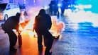 28.05.2024, Berlin: Polizeibeamte versuchen auf der Sonnenallee in Neukölln zwei in Brand gesetzte Mülltonnen zu löschen. In der Sonnenallee kam es zu teilweise gewalttätigen Auseinandersetzungen von Menschen