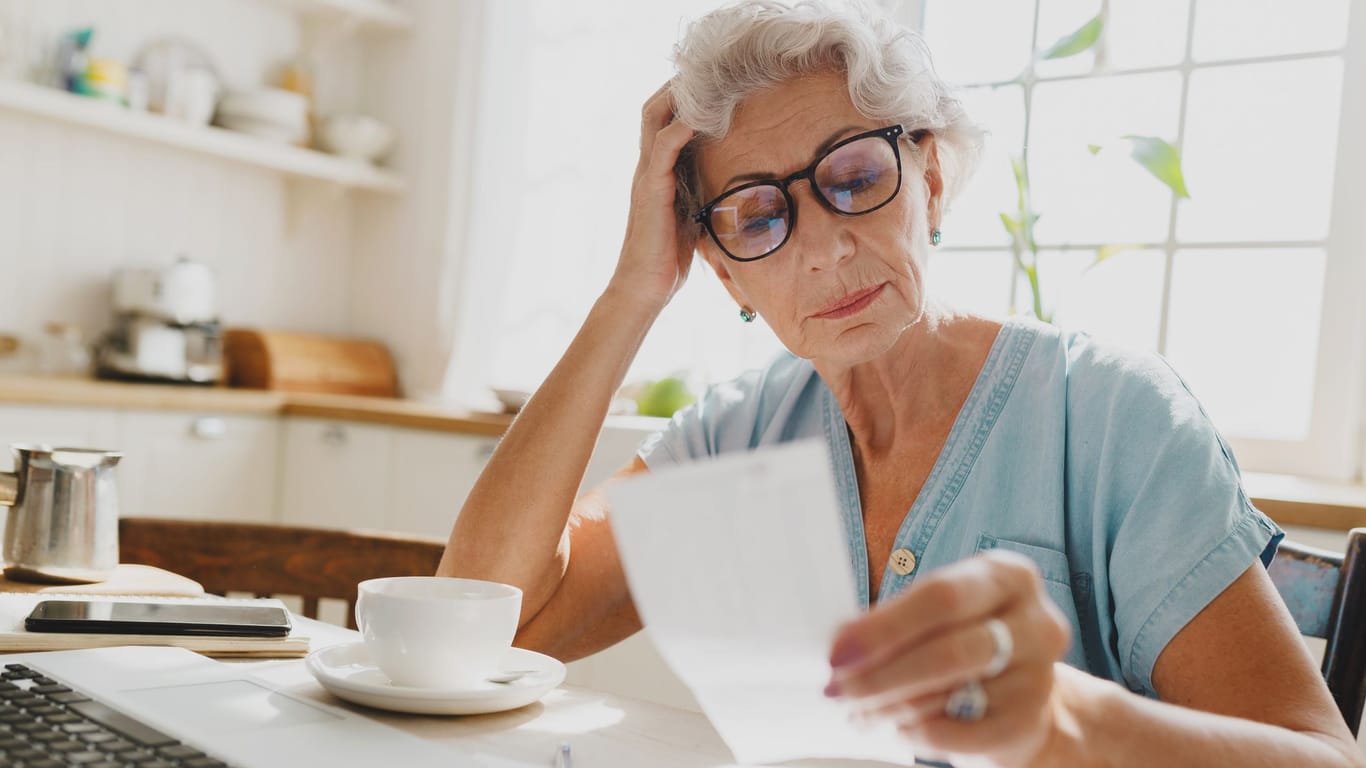 Rentnerin sichtet ein Dokument: Wer als Rentner weiterarbeitet, muss auch selbst Beiträge zahlen, damit die Rente steigt.