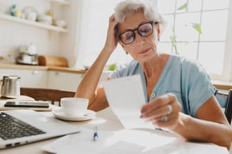 Rentnerin sichtet ein Dokument: Wer als Rentner weiterarbeitet, muss auch selbst Beiträge zahlen, damit die Rente steigt.
