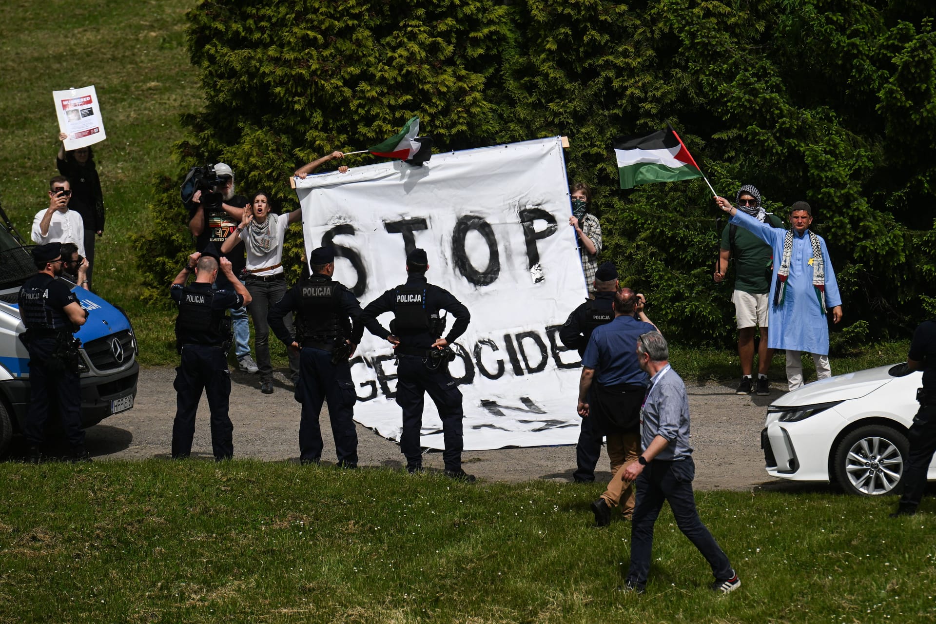 Pro-palästinensische Demonstranten rollen neben dem "Marsch der Lebenden" ein Banner aus, das Israel einen Völkermord an Palästinensern in Gaza vorwirft. Sie stören damit das Gedenken.