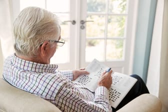 Ein älterer Mann macht ein Kreuzworträtsel.