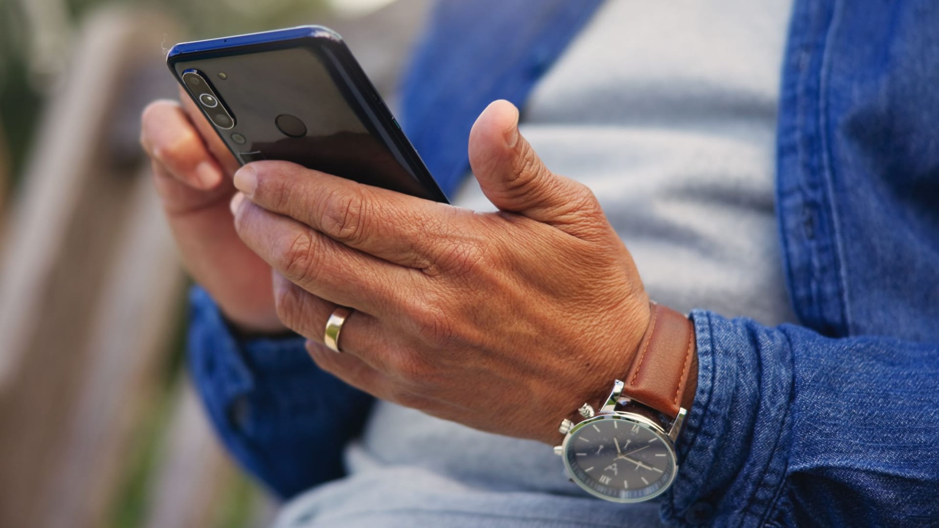 Phone, hands and closeup of senior man networking on social media. mobile app or the internet. Technology, cellphone and elderly male person in retirement scroll on website outdoor in park or garden.