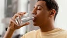 Ein Mann trinkt aus einem Wasserglas (Symbolbild): In England haben sich Dutzende Menschen mit einem Parasiten infiziert.