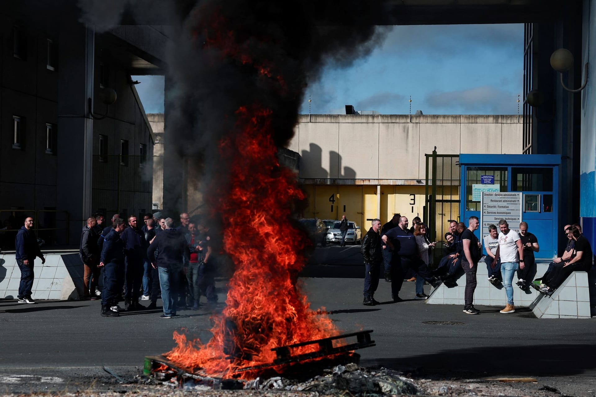 Ein Feuer brennt, während Gefängnispersonal den Eingang des Gefängnisses in Val de Reuil blockiert, in dem der befreite Gefangene inhaftiert war.