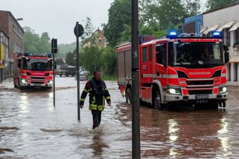 Feuerwehrleute bewegen sich und ihre LKW durch das Hochwasser in der Fischbachstrasse in Saarbrücken.