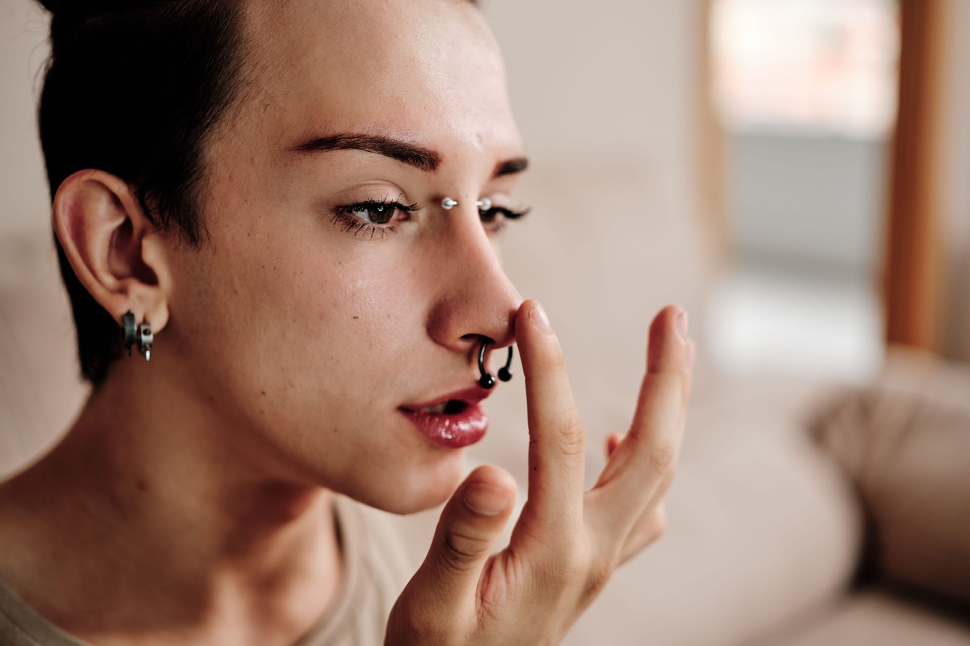 Gay man with piercings making up at home