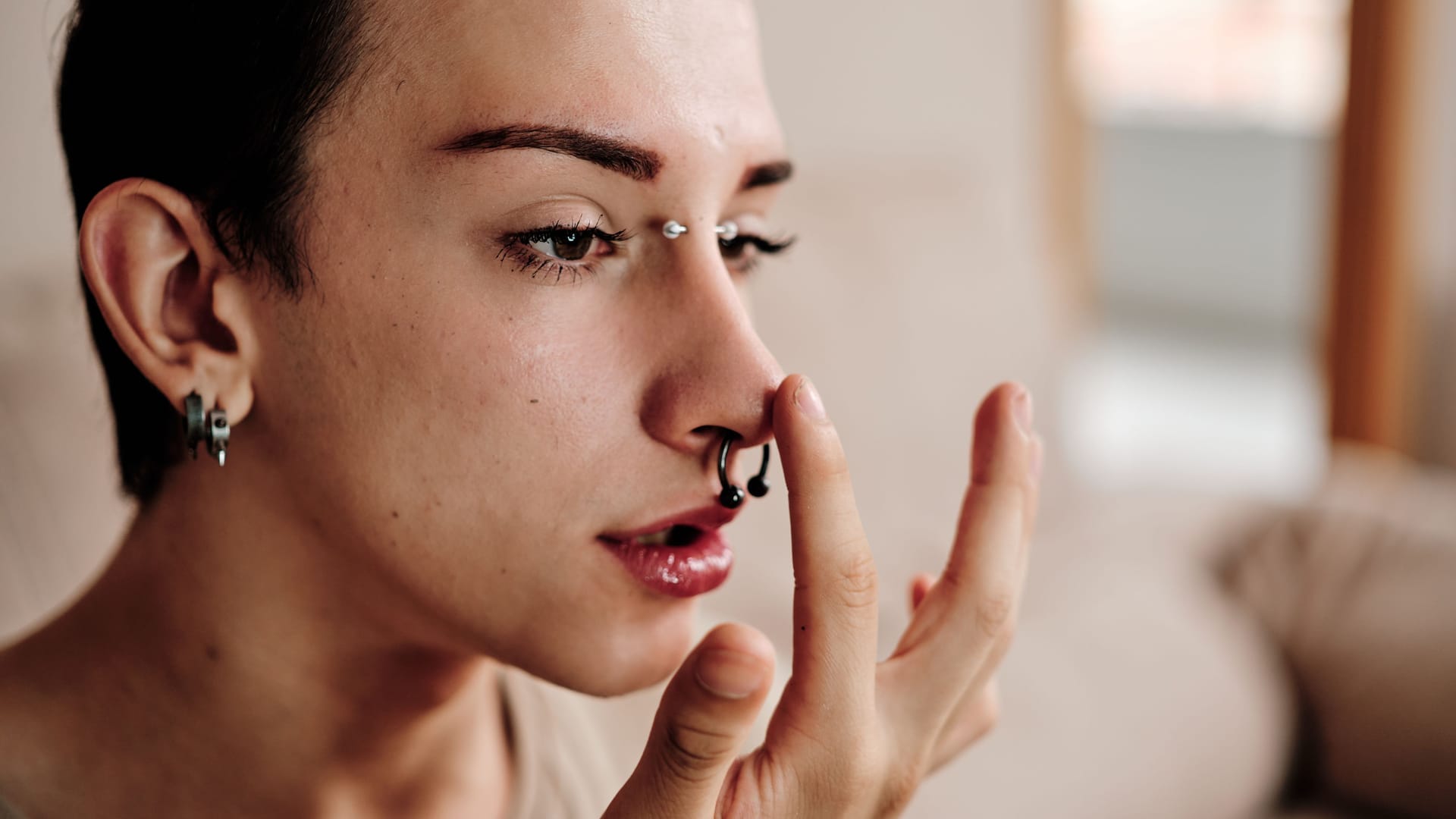 Gay man with piercings making up at home