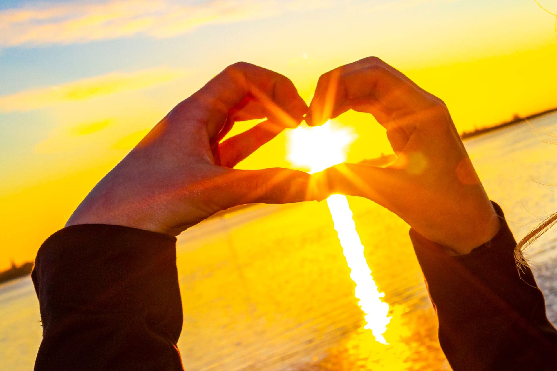 Sunset in the heart formed from hands in Germany.