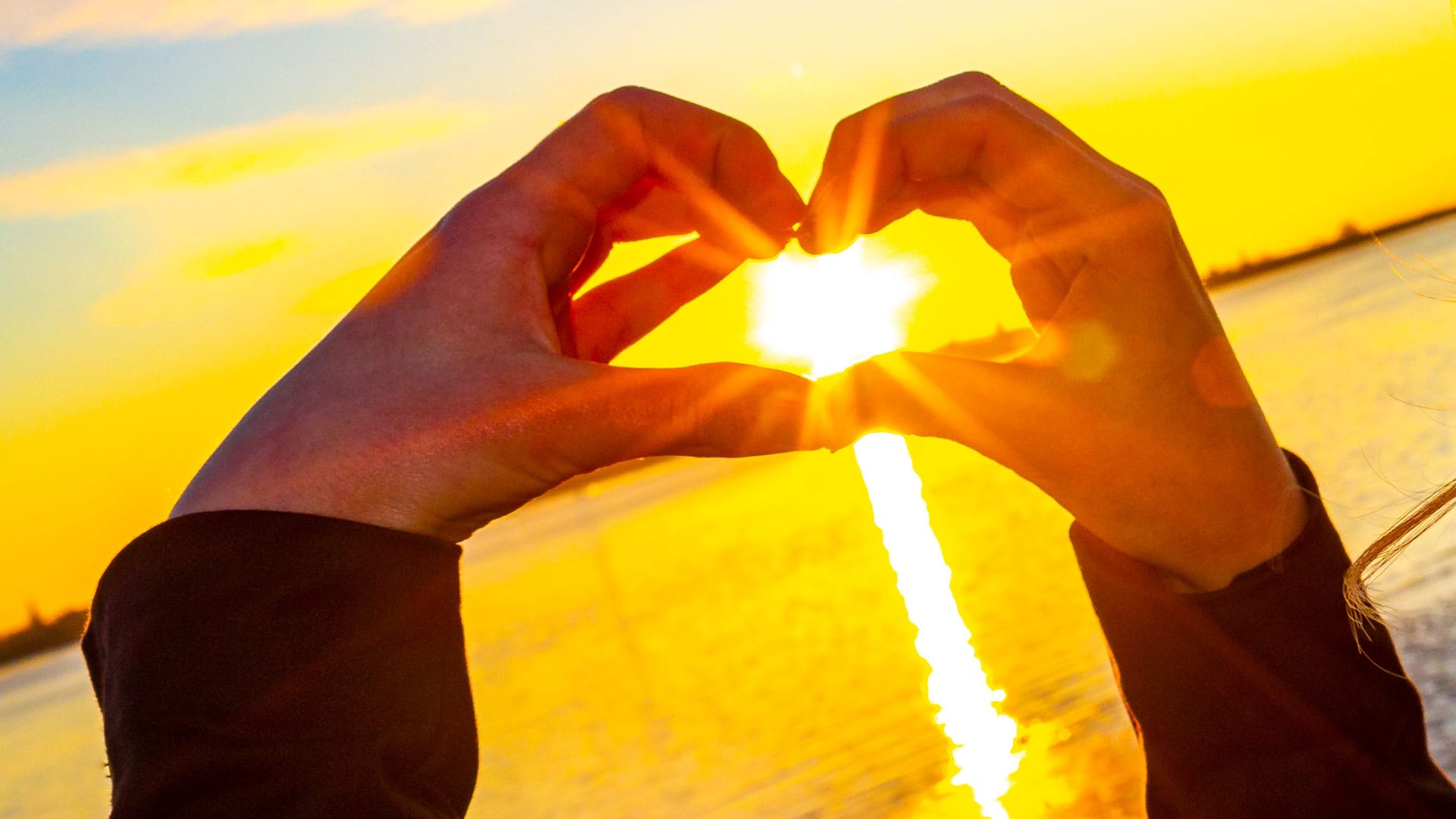 Sunset in the heart formed from hands in Germany.