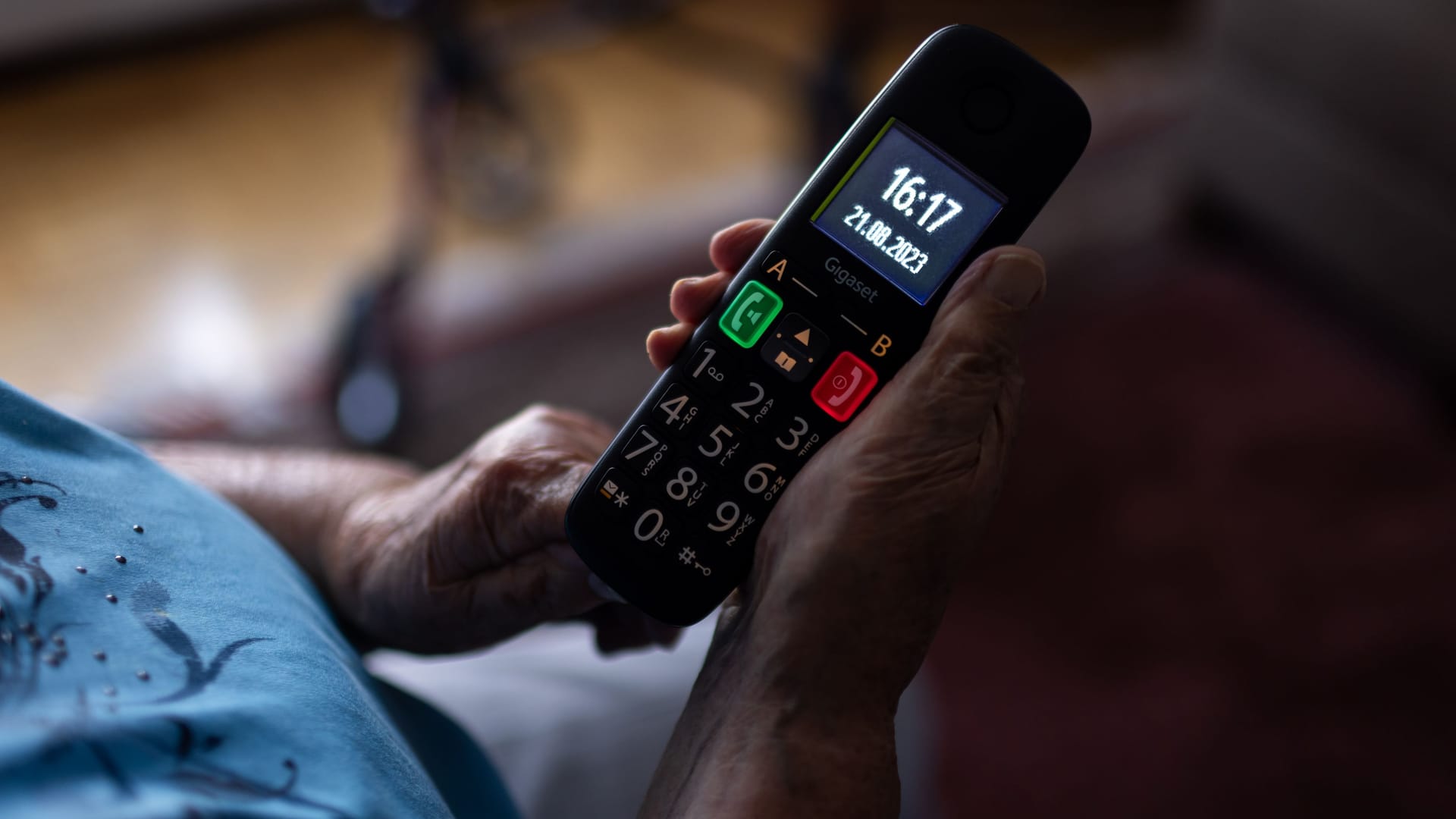 Eine Seniorin hat ein Telefon in der Hand (Archivbild): In Brandenburg ist eine ältere Frau um eine hohe Summe betrofen worden.