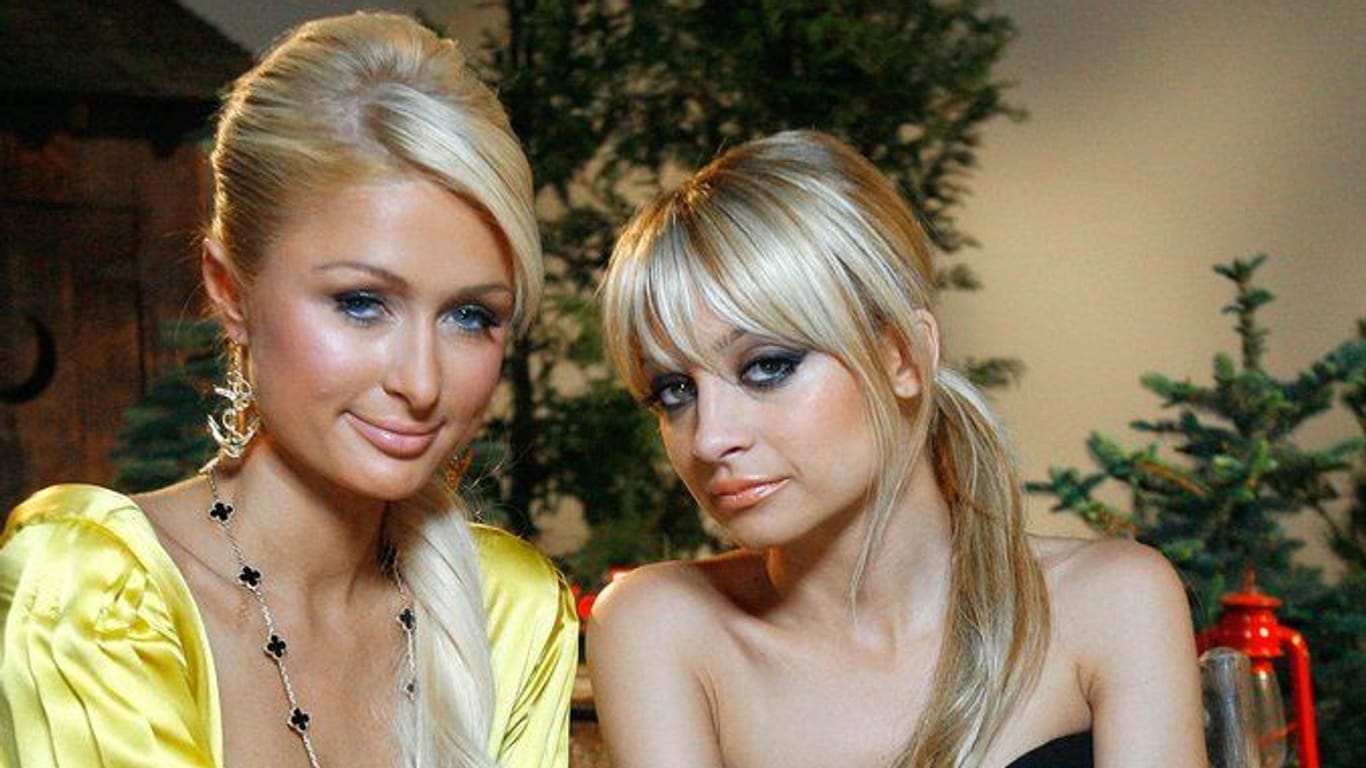 Paris Hilton und Nicole Richie sitzen auf einer Bank und posieren für ein Foto.