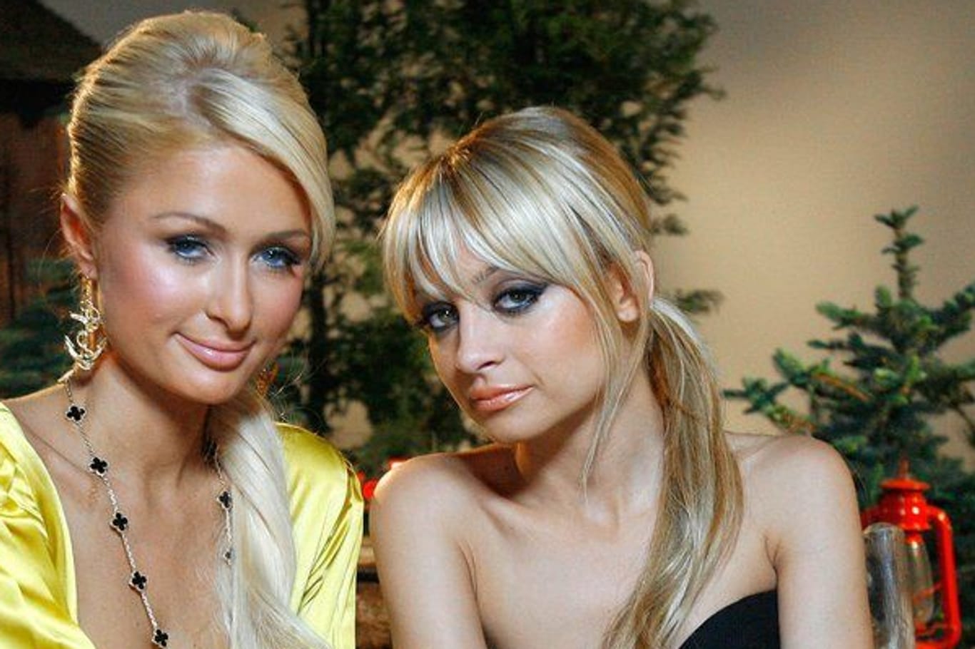 Paris Hilton und Nicole Richie sitzen auf einer Bank und posieren für ein Foto.