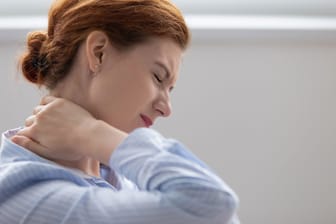 Frau fasst sich vor Schmerzen an den Nacken
