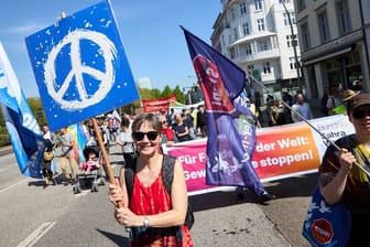 Eine Demonstrantin hält ein Transparent mit dem Peace-Symbol hoch: Der DGB rechnete in Hamburg mit rund 3000 Teilnehmenden.