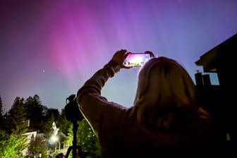 Eine Frau fotografiert die Polarlichter über München-Riem: Mit etwas Glück sind diese am Samstag noch einmal zu sehen.