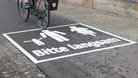 Auf den neuen Warnhinweisen ist ein Radfahrer und ein Elternteil mit Kind zu sehen ist. Darunter steht: "Bitte langsam".
