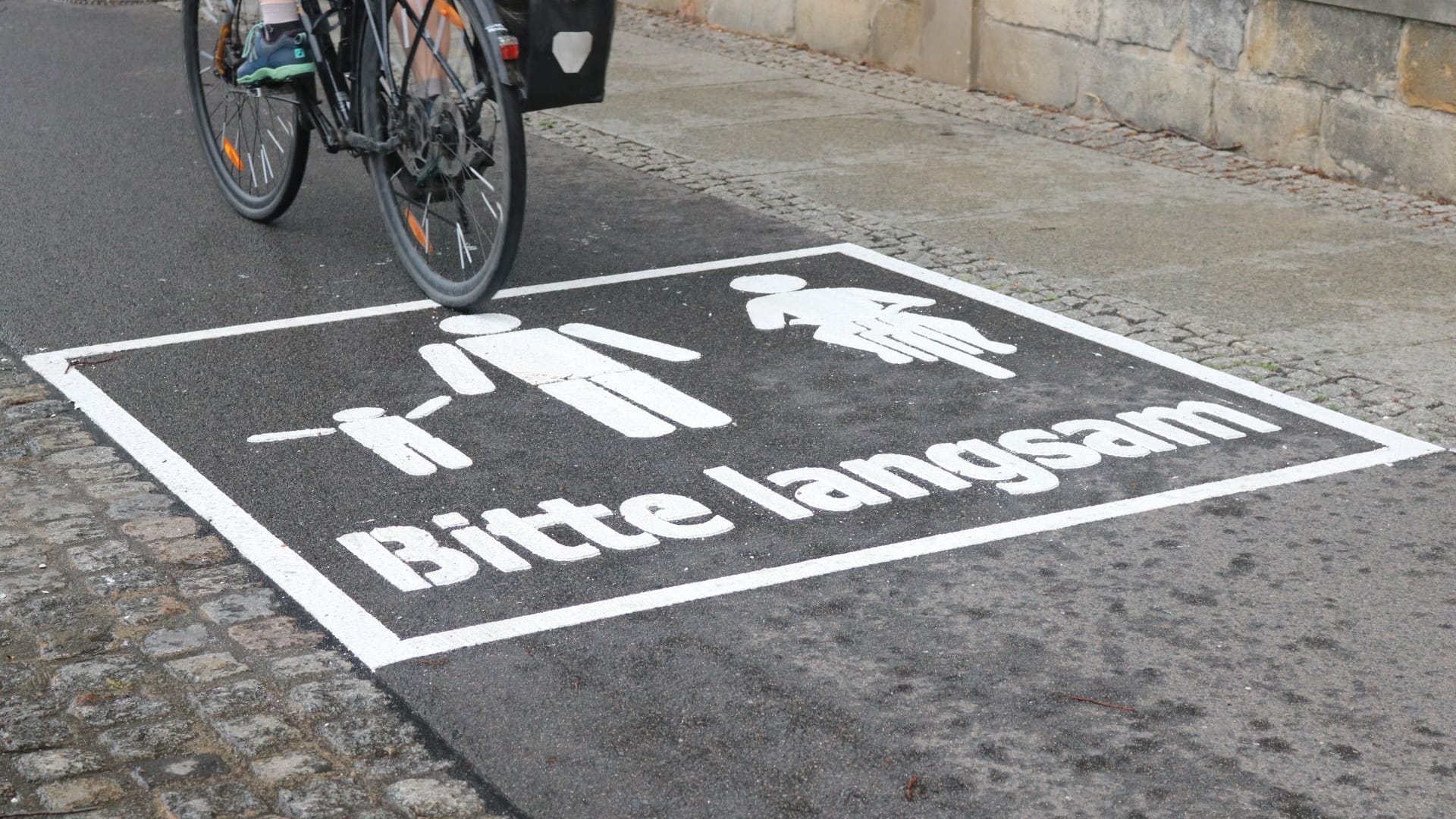 Auf den neuen Warnhinweisen ist ein Radfahrer und ein Elternteil mit Kind zu sehen ist. Darunter steht: "Bitte langsam". Auf den neuen Warnhinweisen ist ein Radfahrer und ein Elternteil mit Kind zu sehen ist. Darunter steht: "Bitte langsam".