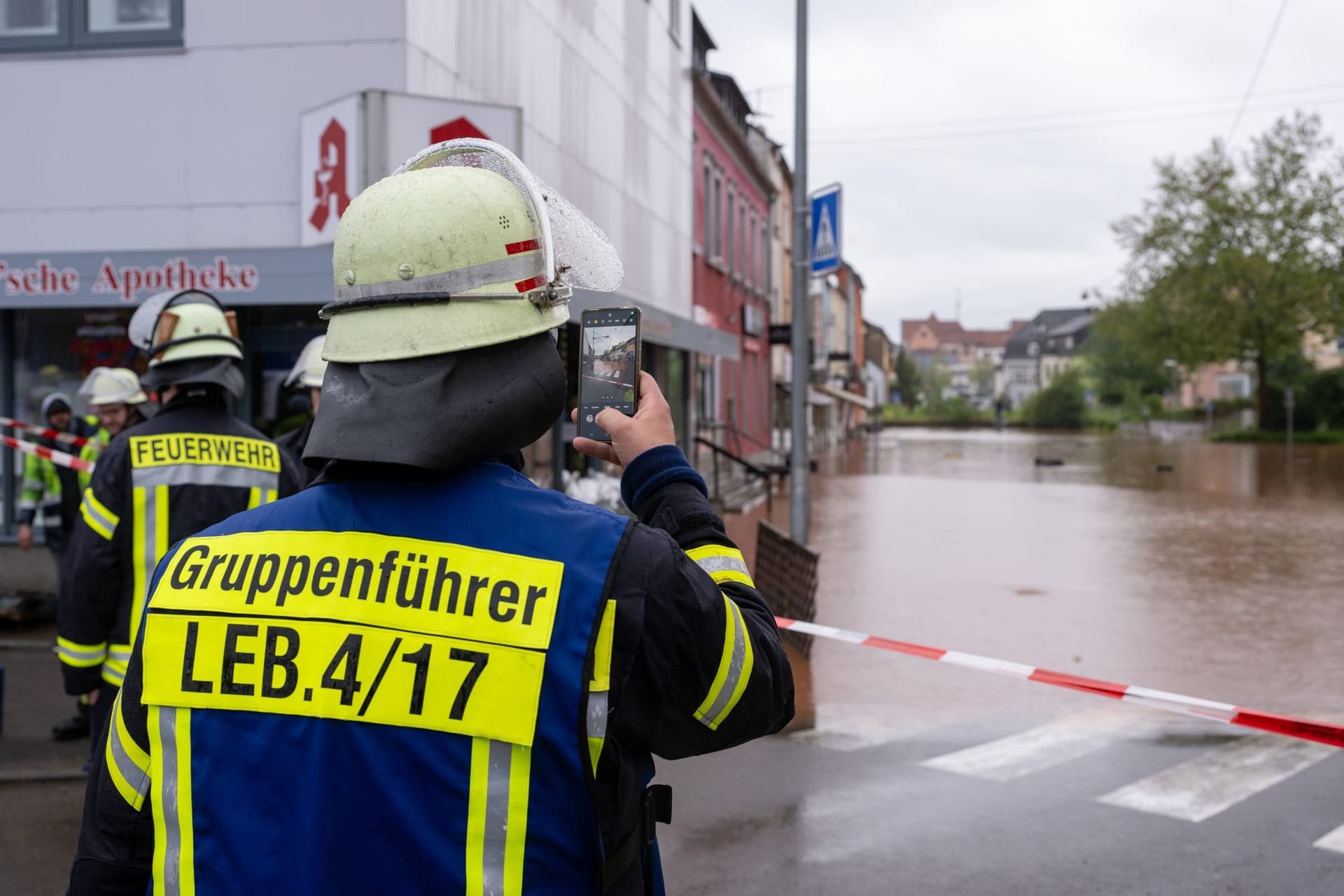 Ein Feuerwehrmann fotografiert das Hochwasser der Theel in der Innenstadt von Lebach