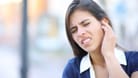 Frau mit Ohrenschmerzen: Bei einer Gehörgangsentzündung zeigt sich mitunter Ausfluss aus dem Ohr.