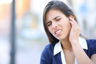 Frau mit Ohrenschmerzen: Bei einer Gehörgangsentzündung zeigt sich mitunter Ausfluss aus dem Ohr.