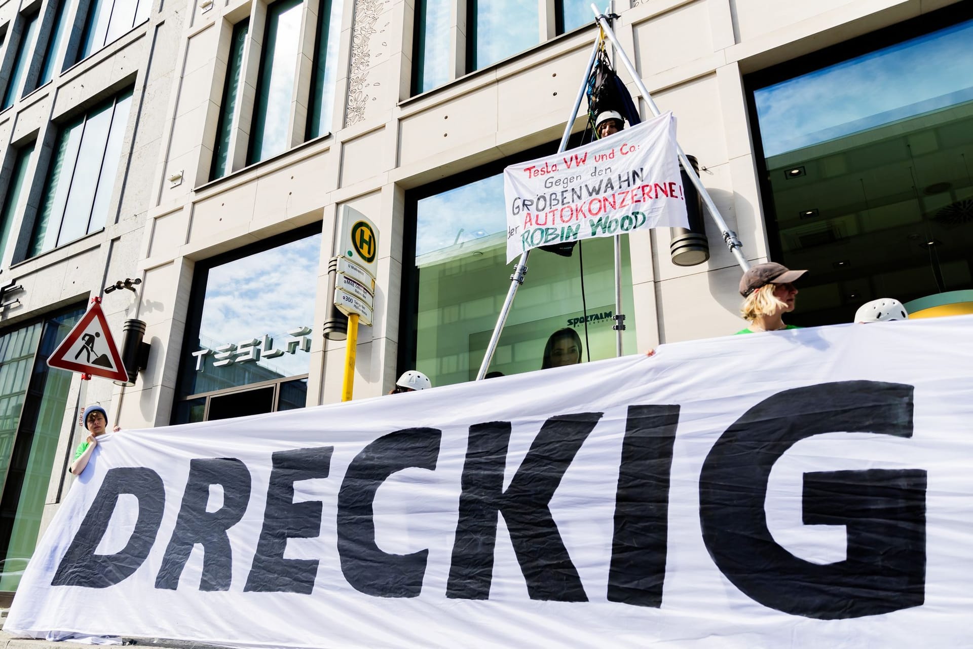 10.05.2024, Berlin: «Dreckig» steht bei einer Protestaktion der Umwelt- und Naturschutzorganisation Robin Wood gegen die geplante Tesla-Werkserweiterung in Grünheide vor dem Tesla Store in der Mall of Berlin auf einem Transparent