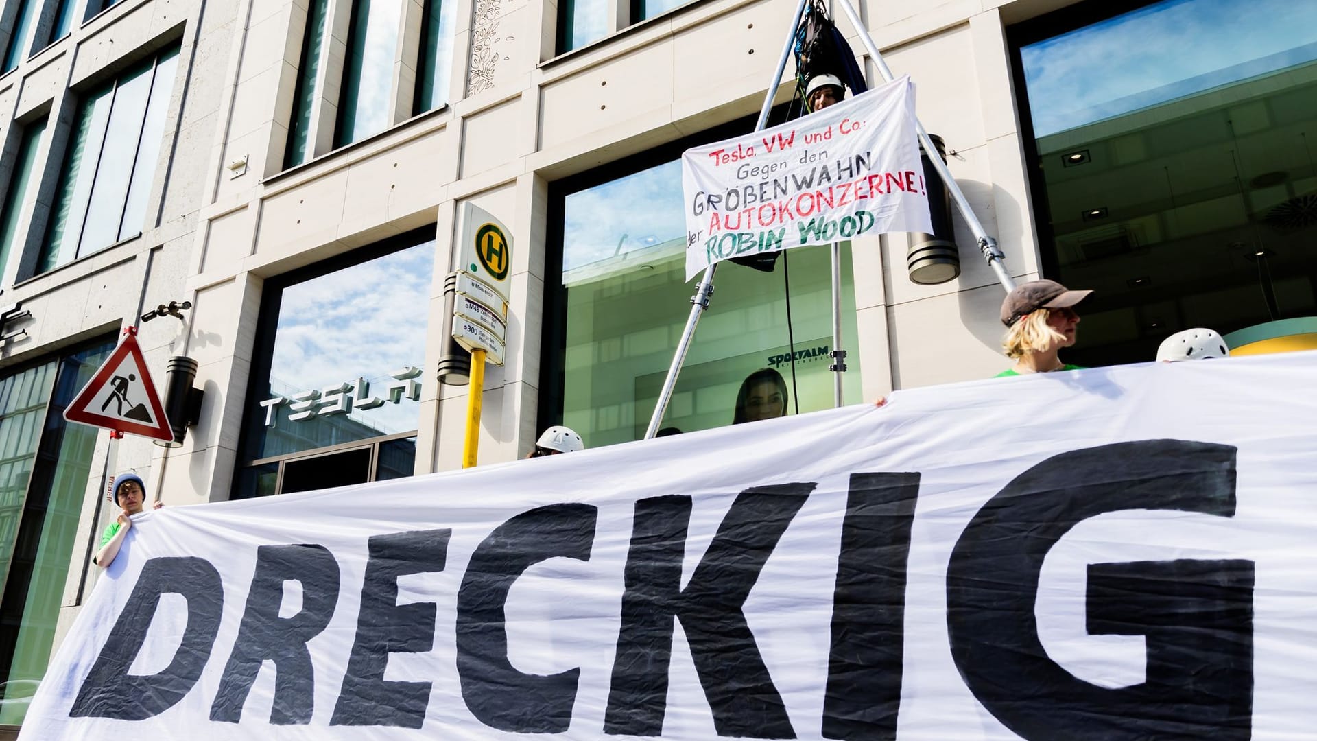 10.05.2024, Berlin: «Dreckig» steht bei einer Protestaktion der Umwelt- und Naturschutzorganisation Robin Wood gegen die geplante Tesla-Werkserweiterung in Grünheide vor dem Tesla Store in der Mall of Berlin auf einem Transparent