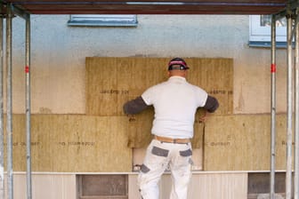 Ein Handwerker dämmt die Fassade eines Hauses