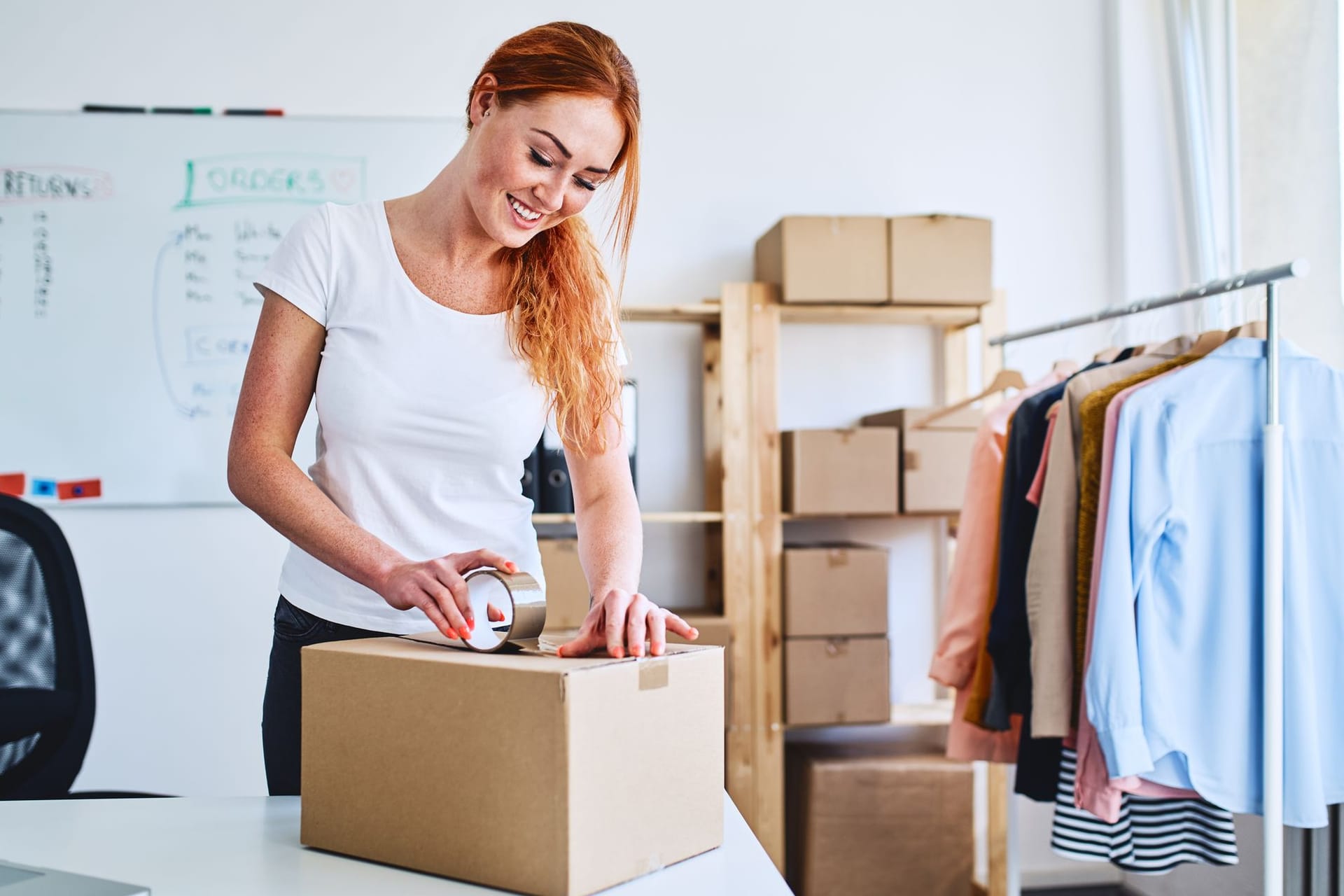 Frau packt Ware in einen Versandkarton