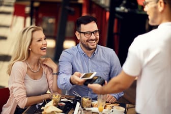 Paar bezahlt nach dem Restaurantbesuch via Smartphone