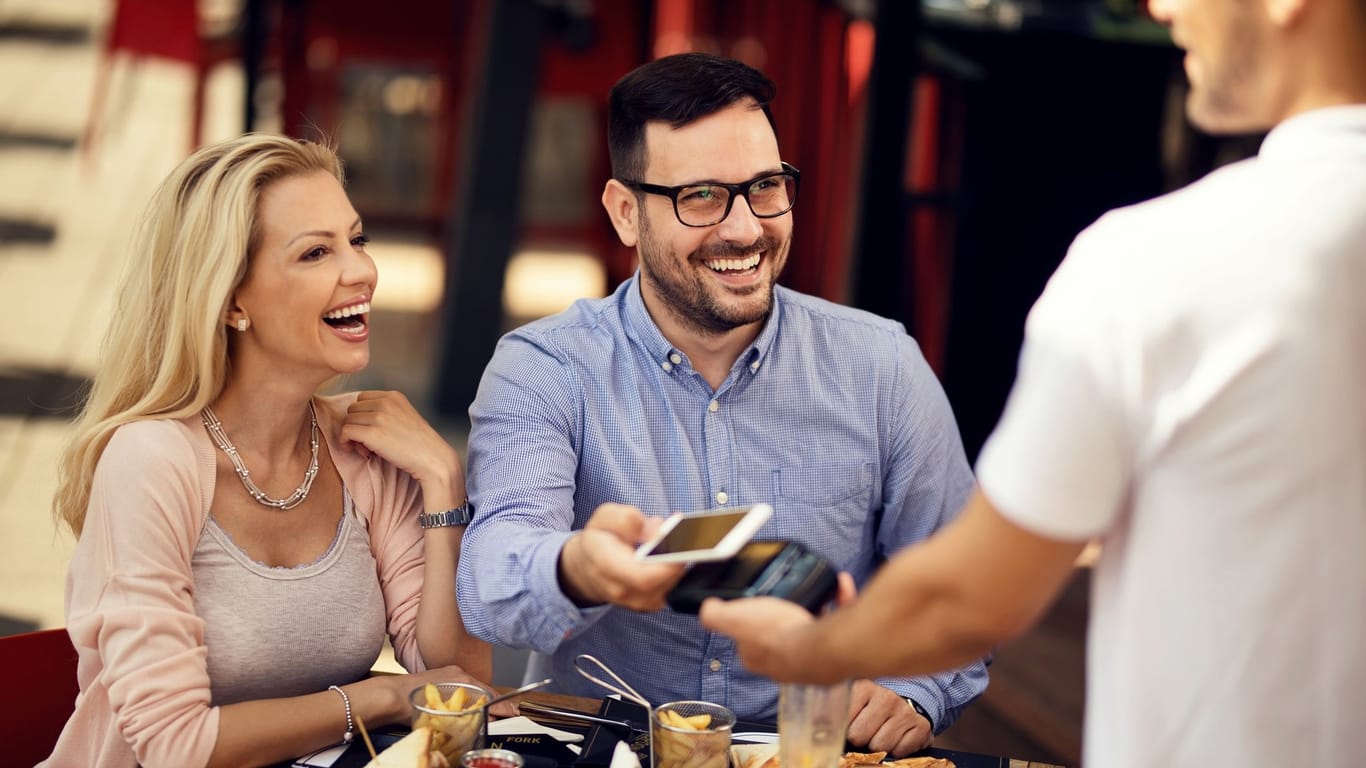Paar bezahlt nach dem Restaurantbesuch via Smartphone