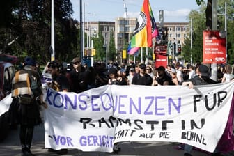 Demonstranten stehen anlässlich einer Kundgebung auf dem Jorge-Gomondai-Platz und halten ein Banner mit Aufschrift "Konsequenzen für Rammstein - vor Gericht statt auf die Bühne". Anlass sind die Konzerte der deutschen Band Rammstein in Dresden.