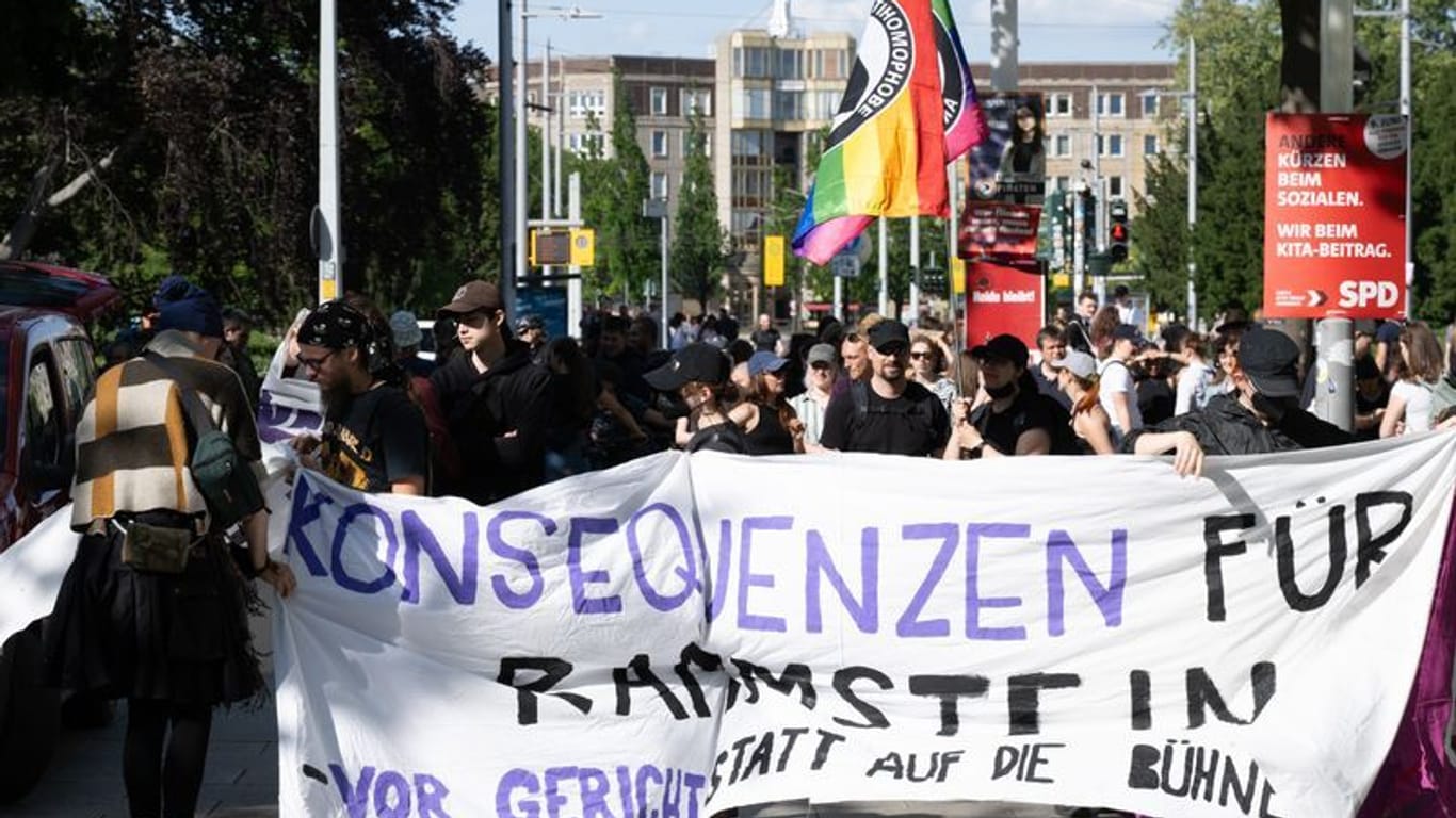 Demonstranten stehen anlässlich einer Kundgebung auf dem Jorge-Gomondai-Platz und halten ein Banner mit Aufschrift "Konsequenzen für Rammstein - vor Gericht statt auf die Bühne". Anlass sind die Konzerte der deutschen Band Rammstein in Dresden.