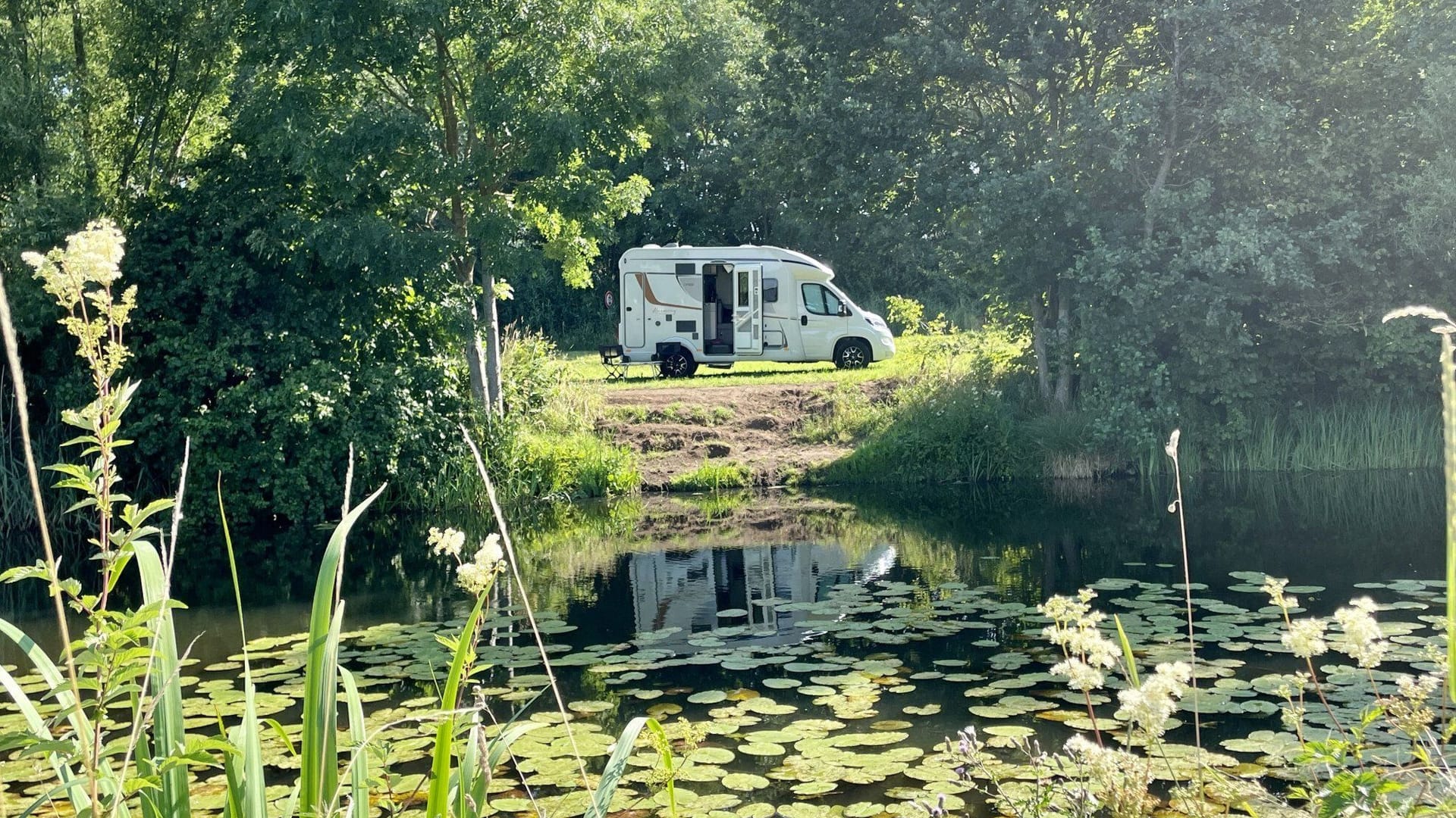 In Barum kann man auf einer Wiese mit Blick auf einen mit Seerosen bedeckten Bachlauf stehen.