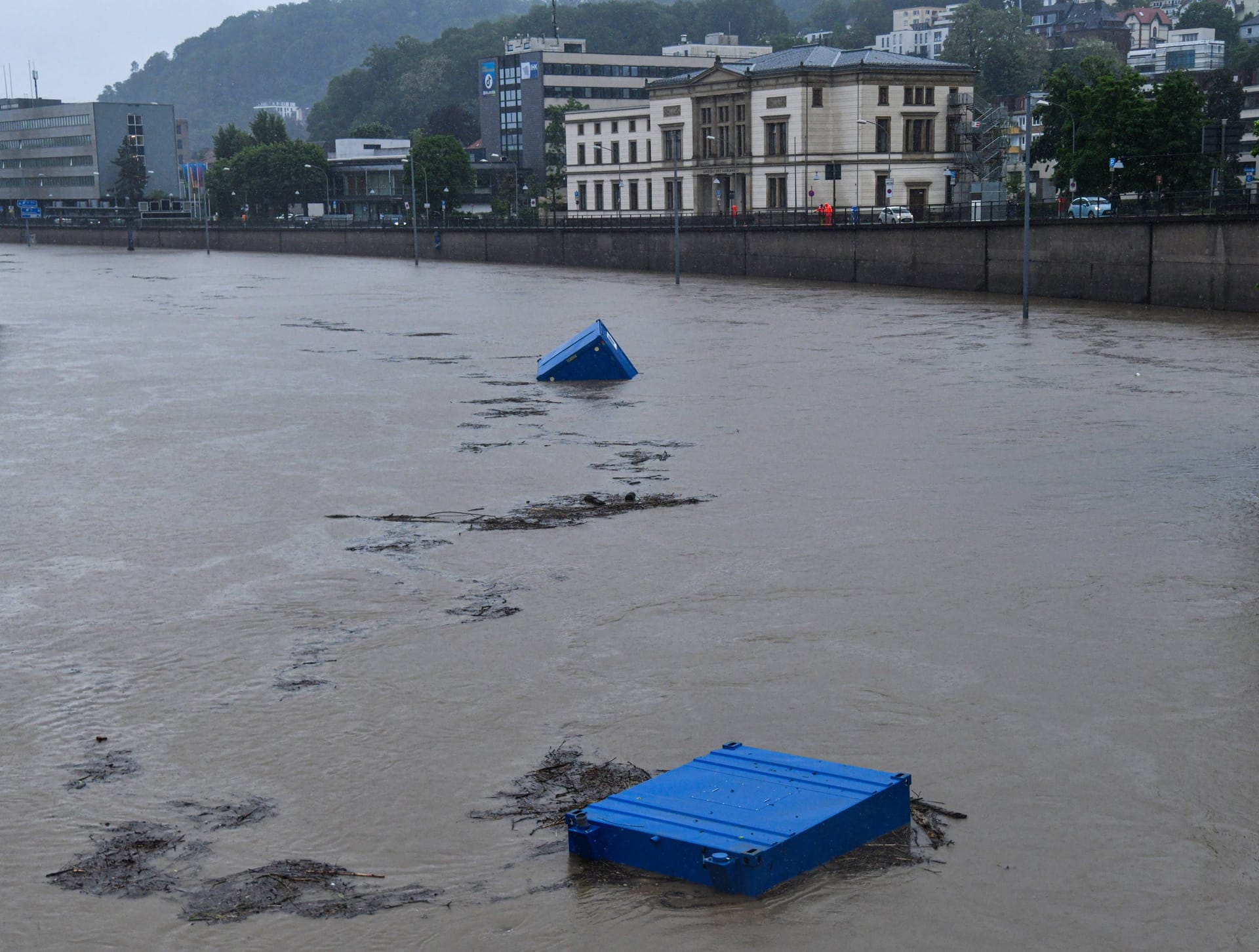 Die Wassermassen haben Baucontainer mitgerissen. Diese schwimmen als Treibgut am saarländischen Landtag vorbei.