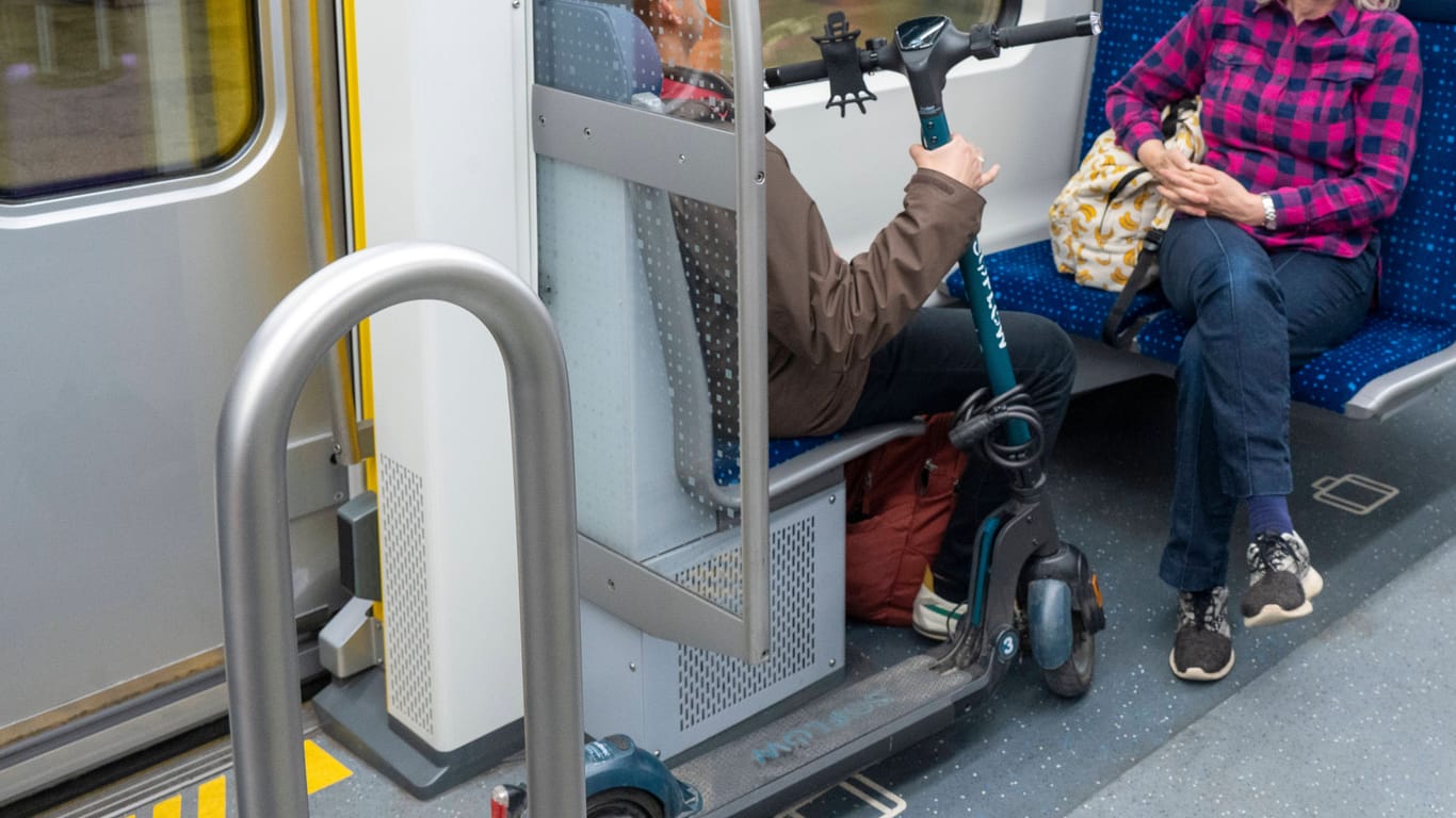 Ein Mensch sitzt mit einem E-Scooter in einer Bahn (Symbolbild): Im Verkehrsverbund Bremen/Niedersachsen ist das ab Juni tabu.