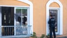 Ein Polizist sichert an einer Tür von einem Restaurant in Hoppegarten Spuren: In dem Restaurant wurde eine Scheibe eingeschlagen, die Fassade beschmiert und Buttersäure verteilt.