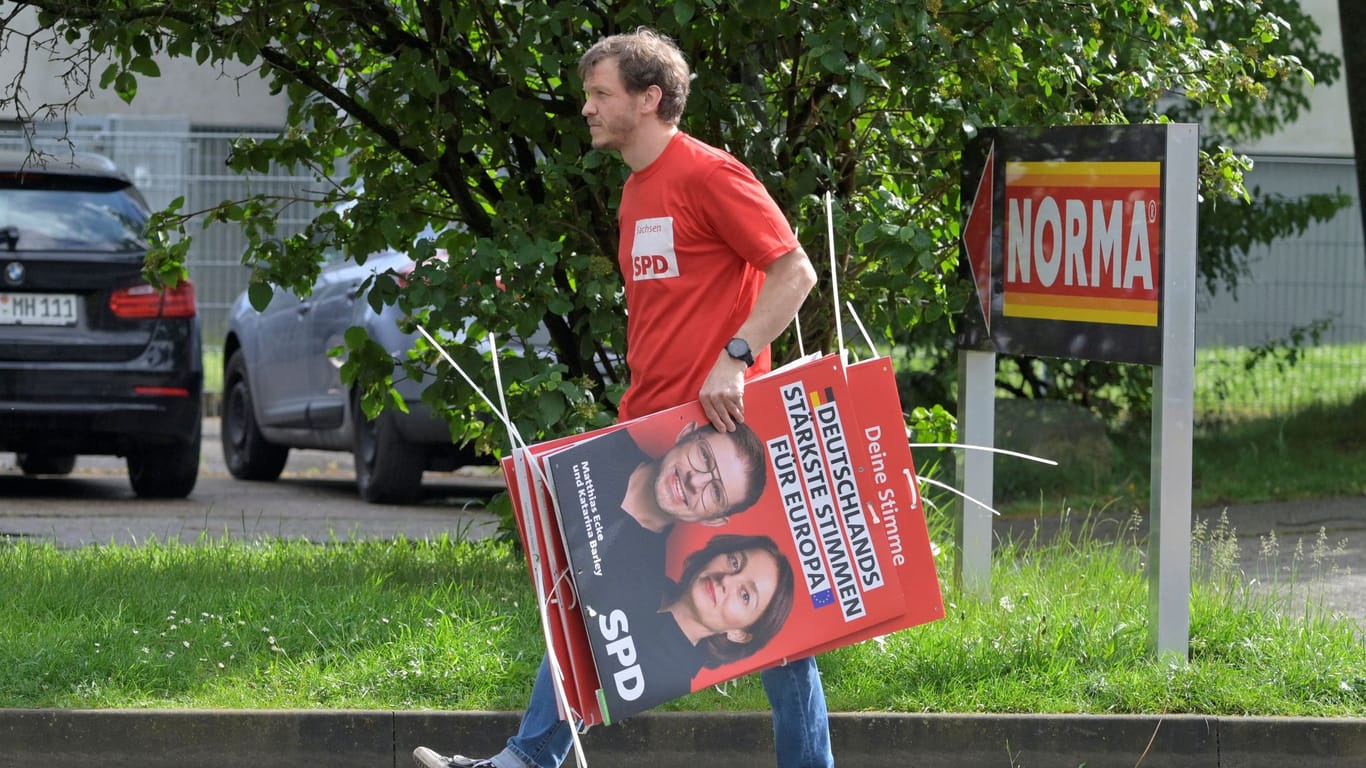 Ein Wahlkampfhelfer der SPD trägt ein Plakat mit Politiker Matthias Ecke: Ecke wurde Opfer eines brutalen Angriffs.