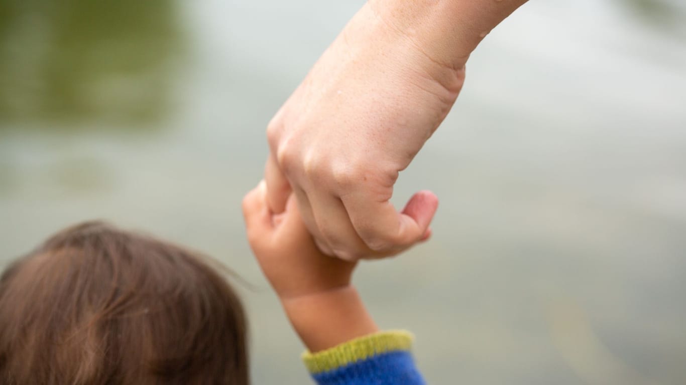 Mutter hält Kind an der Hand