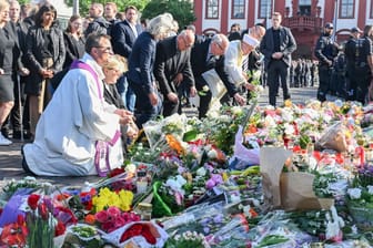 Bei einer Kundgebung unter dem Motto "Mannheim hält zusammen", die anlässlich einer Messerattacke stattfindet, bei der ein Polizist getötet wurde, legen Geistliche verschiedener Konfessionen Blumen nieder.
