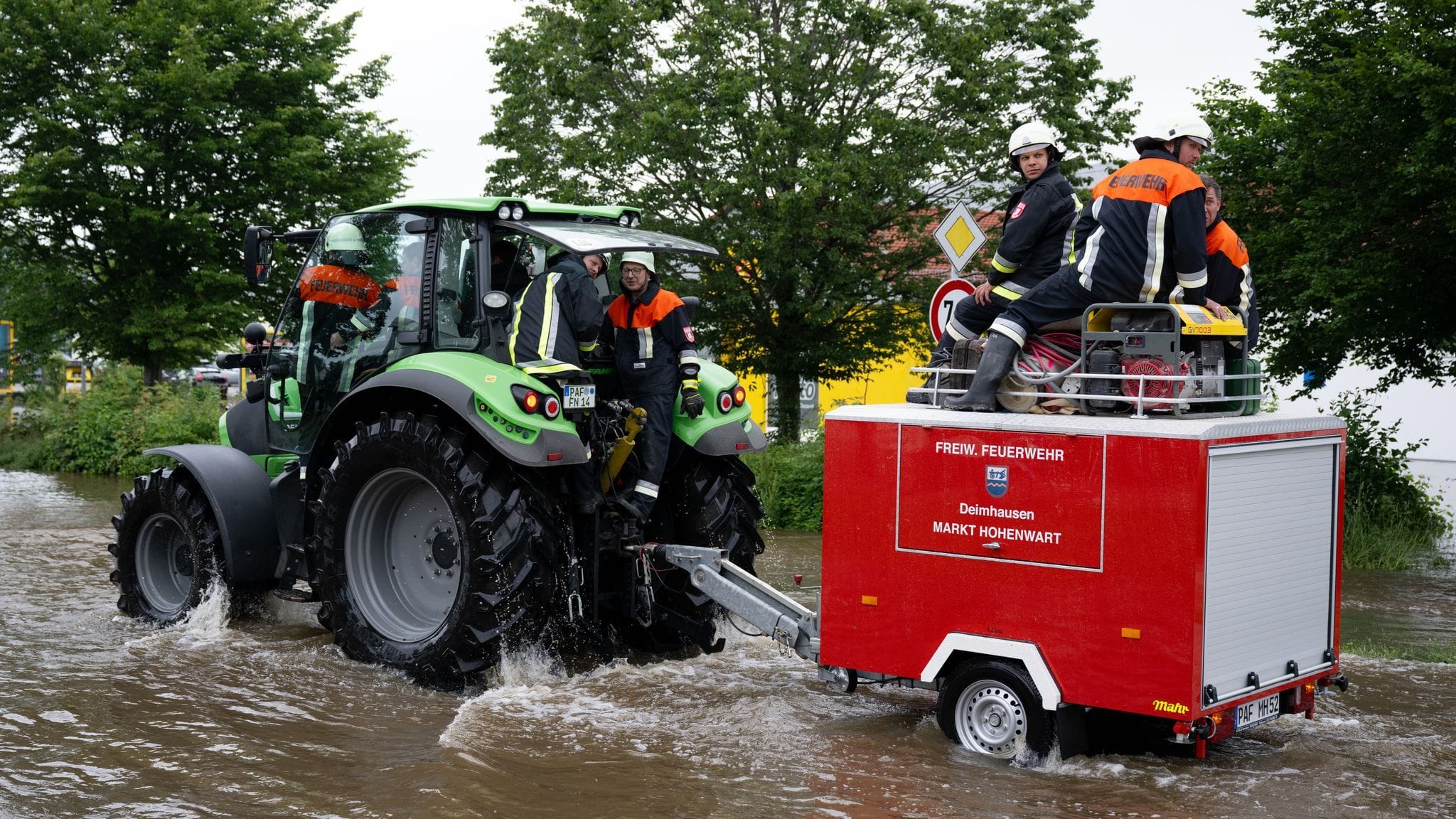 Bayern, Reichertshofen: Feuerwehrleute wissen sich zu helfen und fahren mit einem Feuerwehr-Traktor durch das Hochwasser.