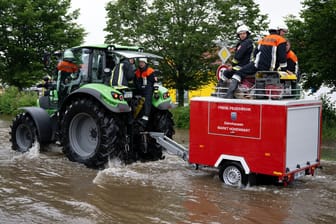Bayern, Reichertshofen: Feuerwehrleute wissen sich zu helfen und fahren mit einem Feuerwehr-Traktor durch das Hochwasser.
